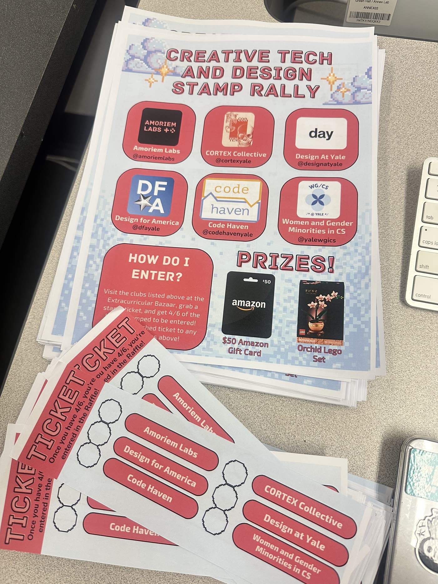 A stack of year 1 flyers for the Creative Tech and Design Stamp Rally, with the six clubs and the prizes, beside paper stamp tickets with a space for each club